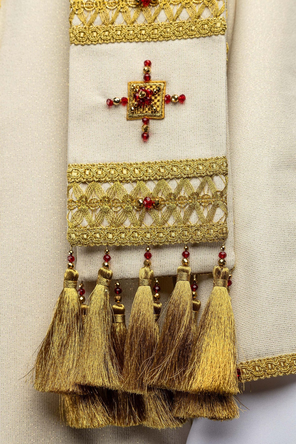 Casula avorio, dettaglio del bordo decorato con ricamo, pietre e nappe dorate