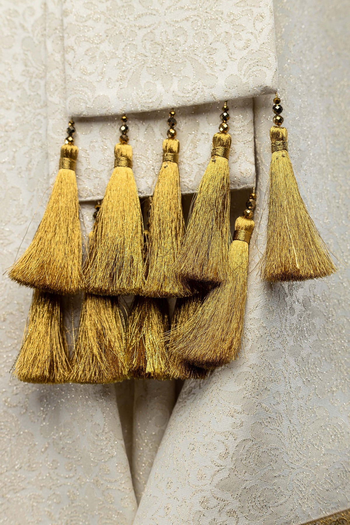 Casula avorio, dettaglio delle nappine dorate con perline